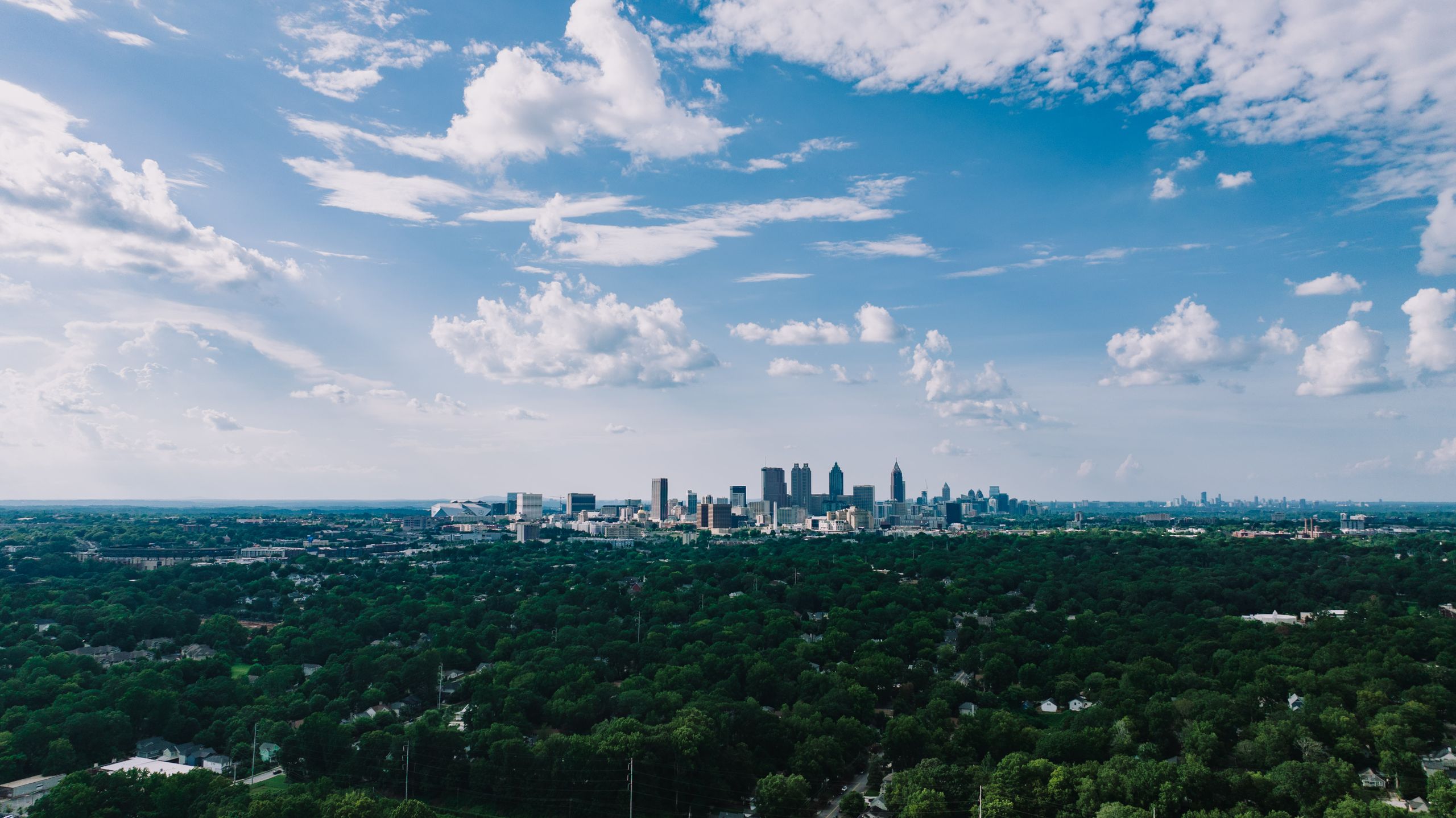 Stunning aerial view of Atlanta's skyline with lush greenery under a vibrant blue sky.